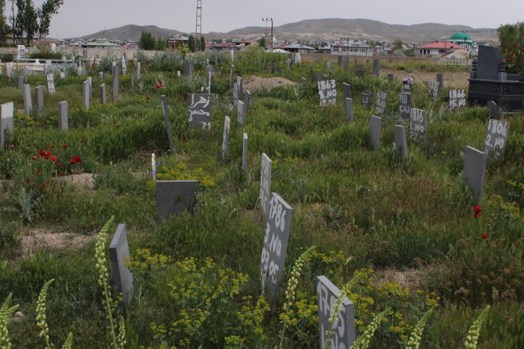 Photo Title and the year: Numerology of the irregular migrant Death-2023The place the photo taken: Northern Kurdistan – Eastern Turkey
Explanation: No personal identification tags are present in the Cemetery of the Nameless; no name, family name or date of birth. There are two numbers written on the tombstone, one of which is the date the dead body was found in the border area. The second number is provided by the Directorate of the Cemeteries Affairs of the city Municipality which serves as a bureaucratic archival method.