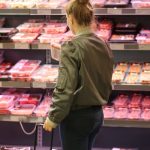 Customer looking down at meat product in the store.