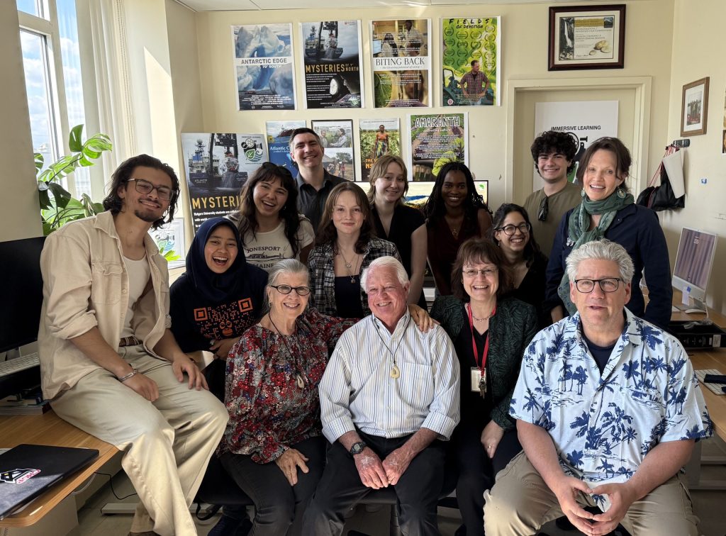 Students and faculty from The Storytelling Lab posing for a photo with donors Don and Penny Pray seated at the center within the lab building