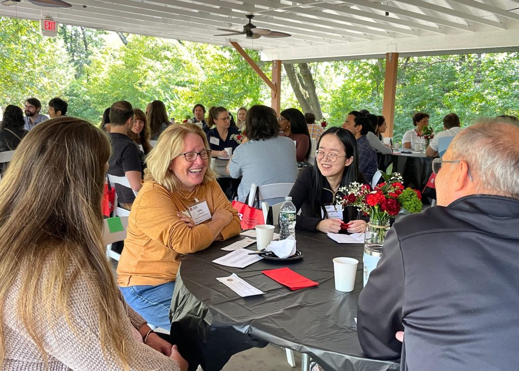 Retreat attendees seated at multiple round circles, meeting with and talking to each other 