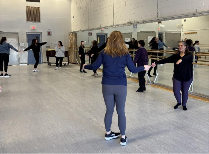Inside a mirror-lined dance practice room, Cristina Marte teaches students, who are practicing in the background