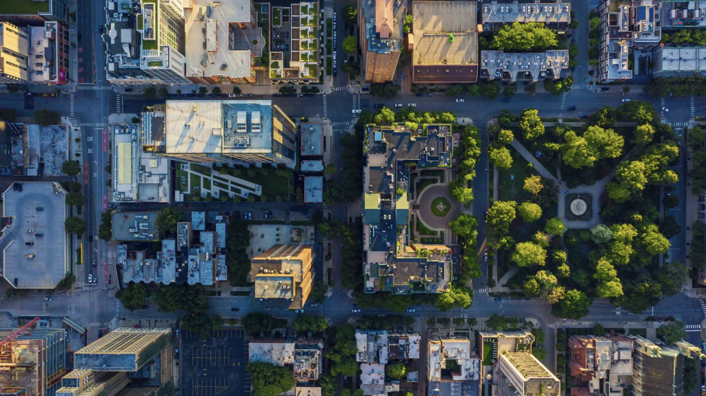 Bird's eye view of a metropolis city with apartment buildings and patches of green from trees and a small park