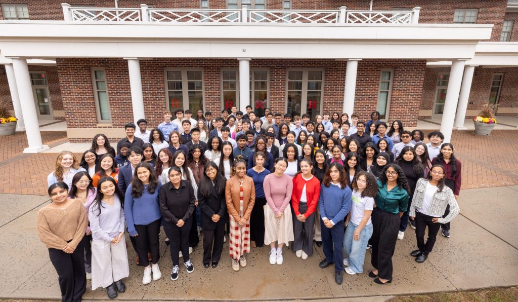 Crowd of students stands smiling for the photo in front of the Ludwig Global Village Learning Center