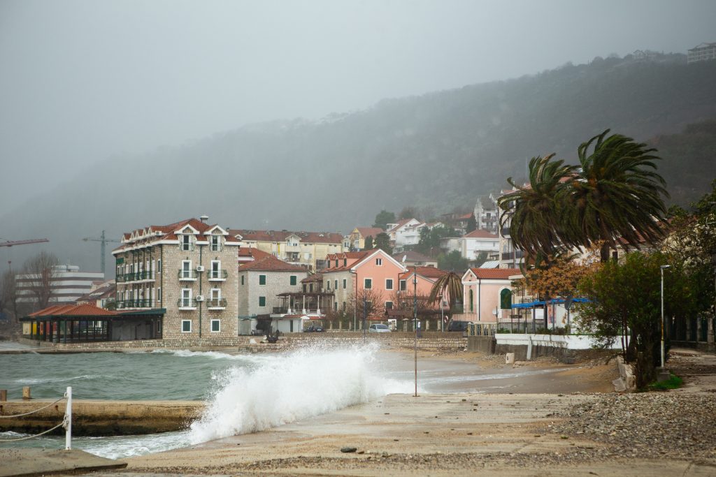 Village on the shore with rising seawaters, waves crashing against the sand