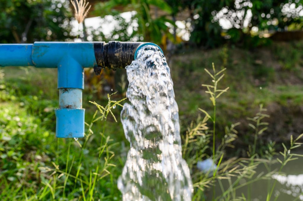 Agriculture pipe with groundwater gushing from it in a forest