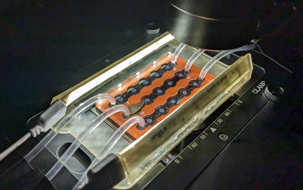 Close up of the machinery behind the microfluidic system, multiple clear tubes attached to a central mechanism