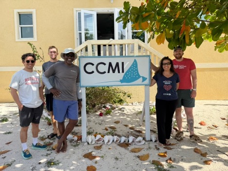 The five mentioned researchers standing around a sign with "CCMI" written on it, in front of a yellow building