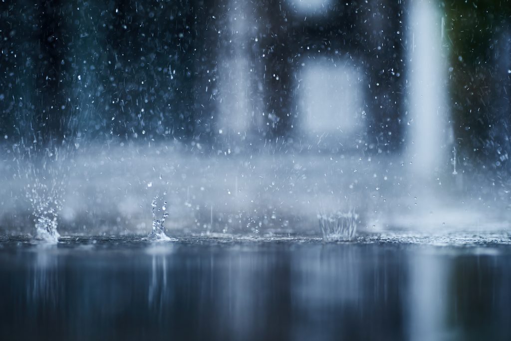 Close up of water droplets splashing down to the concrete floor in large puddles from heavy rain